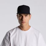 A black and white trucker cap with a logo, worn by a person in a white t-shirt.