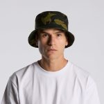 A camo bucket hat in green and black, featuring a wide brim and a fitted design. It includes a branding logo.