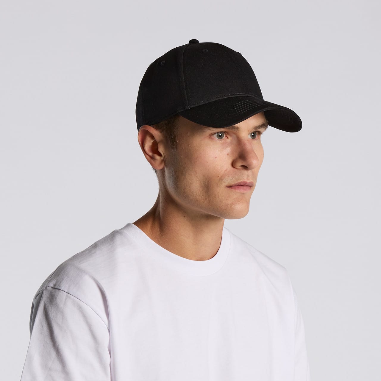 A black cap is worn by a model, featuring a simple design and a logo on the front. A black cap is worn by a model, featuring a simple design and a logo on the front.