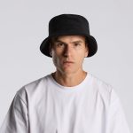 A black Terry Bucket Hat displayed on a model wearing a white t-shirt. The hat features a logo.