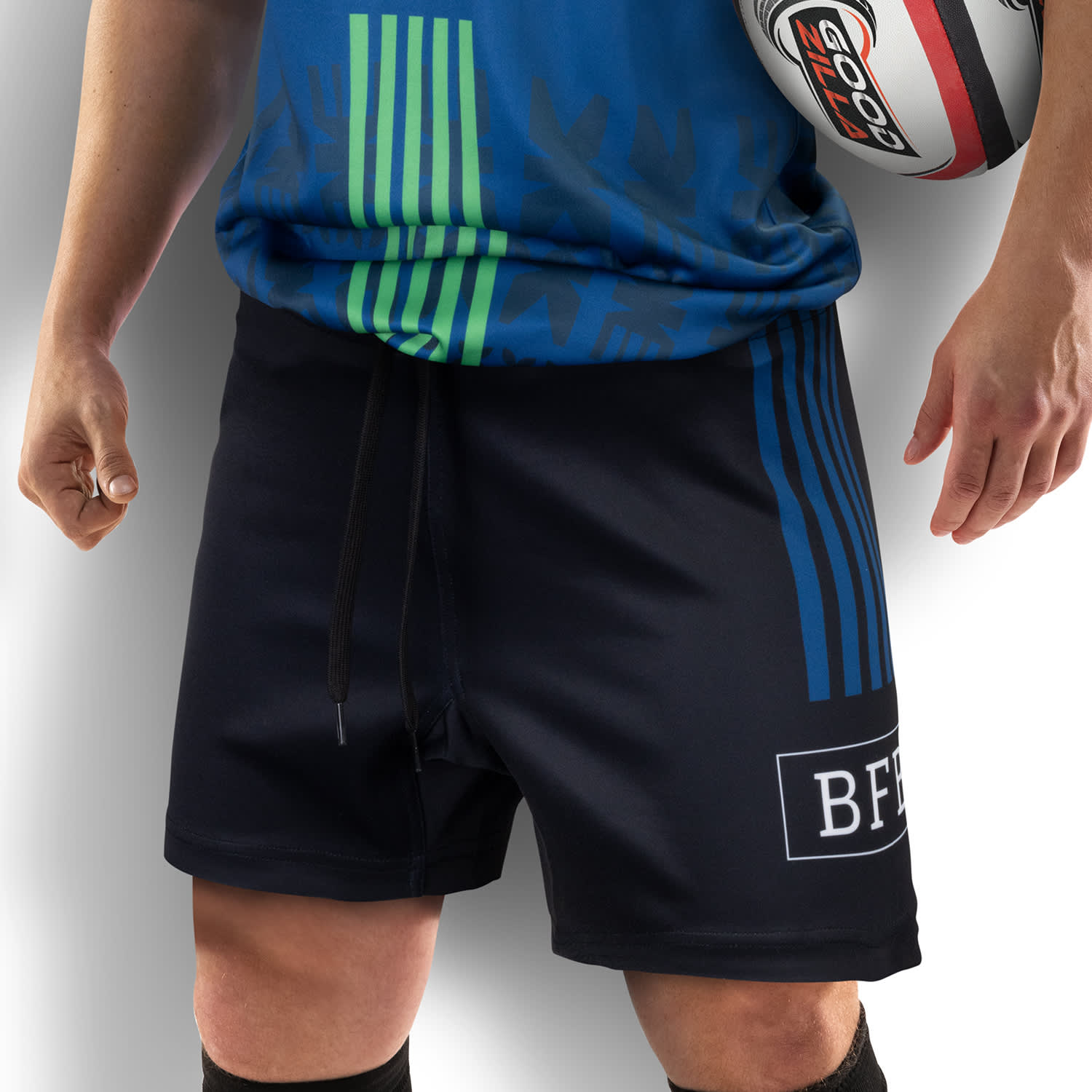 Custom men's rugby shorts in black, featuring blue stripes and a logo, paired with a rugby ball. Custom Mens Rugby Shorts - Image 1