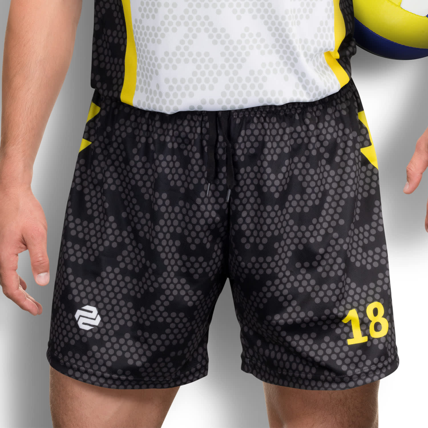 Custom men's volleyball shorts in black with a dotted pattern and yellow accents, featuring a logo and a number. Custom Mens Volleyball Shorts - Image 1