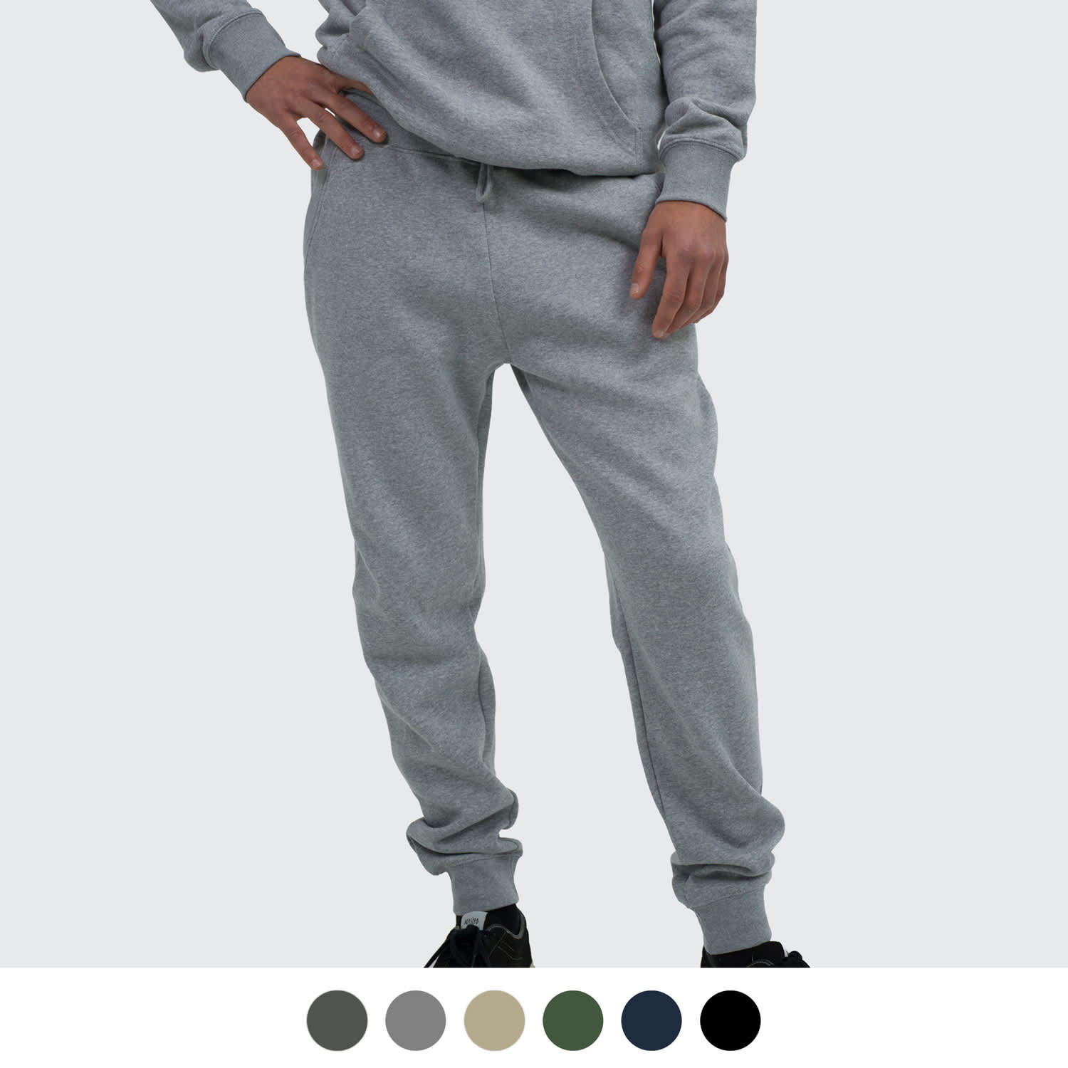 A person wearing grey unisex sweatpants with a relaxed fit, featuring an elastic waistband and cuffed ankles. TRENDSWEAR Haven Unisex Sweatpants - Image 1