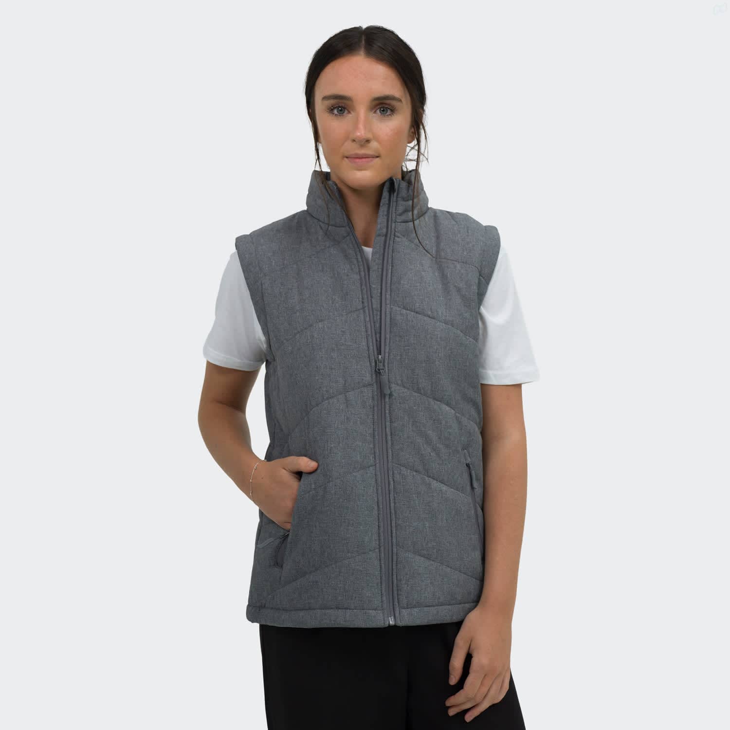 A women's puffer vest in grey, featuring a zip front and side pockets, worn over a white top. TRENDSWEAR Newport Womens Puffer Vest - Image 1