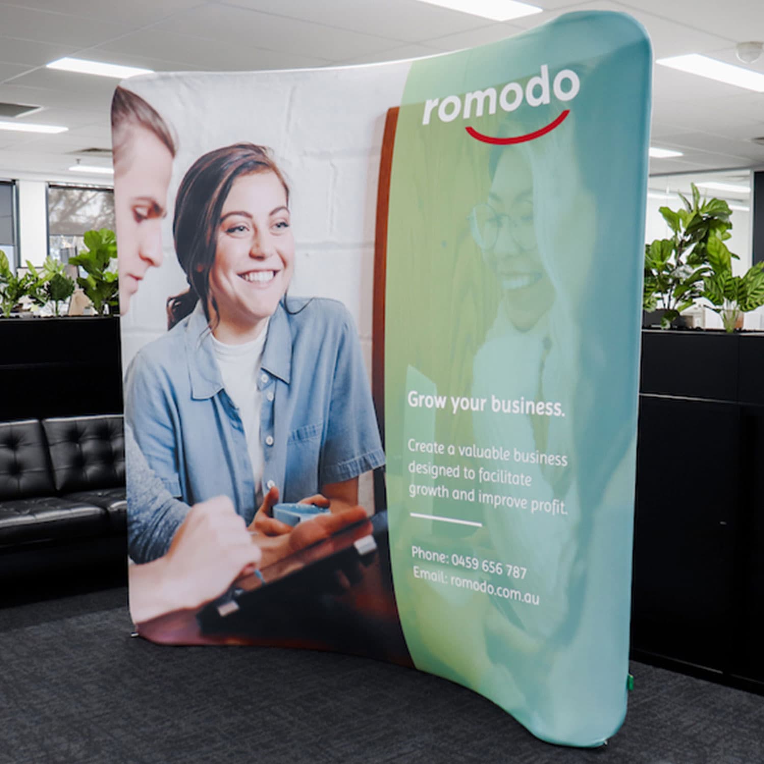 A small curved stretch media wall in green and white featuring images of people and branding elements. Curved Stretch Media Wall Medium - Image 1
