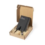 A black notebook, pen, and keychain are presented in a brown gift box with straw filler. The box has a logo.