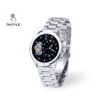 A stylish silver smart watch with a black face and intricate mechanical elements, featuring a branded logo.