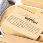 A wireless charger with a wooden design, featuring a card about a limited edition experience and a logo.