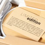 A wireless charger in a wooden box, featuring a card with information and branding, showcasing a limited edition design.