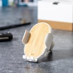 A wireless charger holder featuring a bamboo surface and grey accents, set on a textured surface.