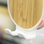 A wireless charger holder featuring a bamboo design, with a white base and an embedded charging symbol.