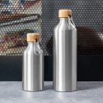 A drink bottle set featuring two stainless steel bottles with wooden tops and a metal clip, both in silver.