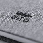 A grey notepad with a textured cover and a logo, featuring a sleek, modern design.