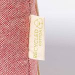 A red and beige laptop pouch with a label indicating it's made from recycled cotton.