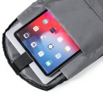 A grey anti-theft backpack with a tablet and a laptop visible inside its interior compartment.