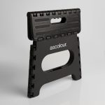 A black folding stool with a textured surface and a handle, featuring a logo on the front.