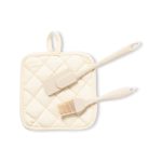 A cream-coloured quilted pot holder with a silicone spatula and a basting brush. The set has a simple design and a logo.