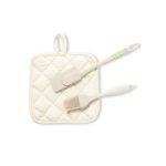 A cream quilted pot holder with a beige spatula and a brush, featuring green detailing on the handle.