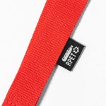 A red lanyard with a fabric tag indicating material composition, featuring a small logo.