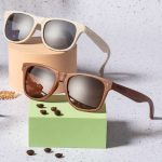 Two pairs of sunglasses displayed on pastel-coloured blocks; one is cream and the other is brown wood.