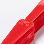 A red Pumik hand fan with a textured handle, featuring a logo and eco-friendly material marking.