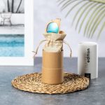 A pair of turquoise sunglasses is presented in a natural fibre pouch, housed in a cylindrical cardboard box.