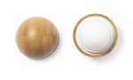 A round lip balm in a natural textured container, featuring a white balm inside. The product has a subtle brown colour.