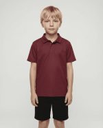 A maroon polo shirt designed for kids, worn by a child, paired with dark shorts. The shirt features a logo.
