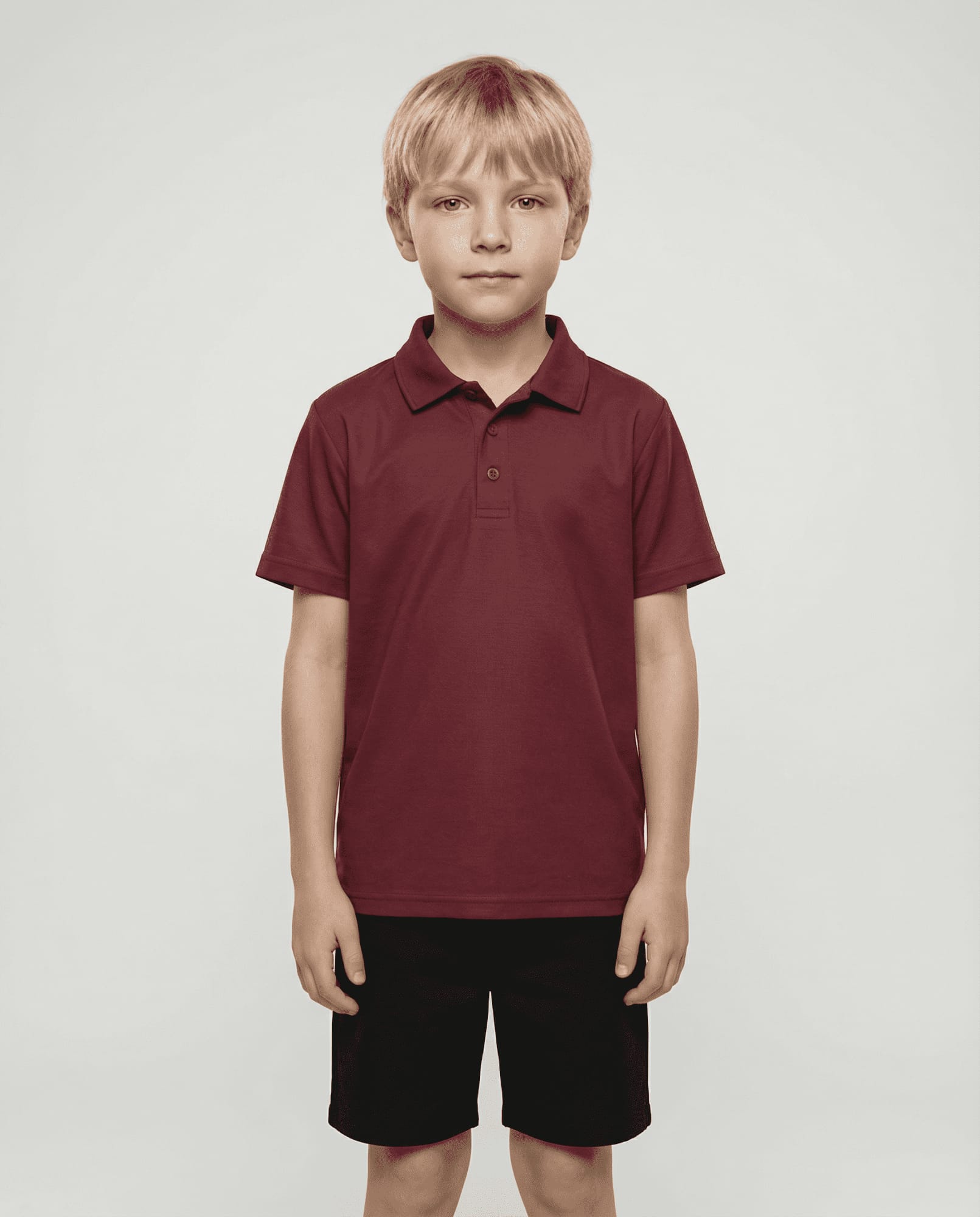 A maroon polo shirt designed for kids, worn by a child, paired with dark shorts. The shirt features a logo. A maroon polo shirt designed for kids, worn by a child, paired with dark shorts. The shirt features a logo.