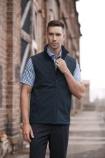 A men's black vest is featured, designed for workwear, with a zip closure and a logo. The model is posing outdoors.