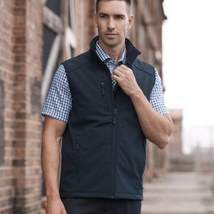 A men's black vest is featured, designed for workwear, with a zip closure and a logo. The model is posing outdoors.