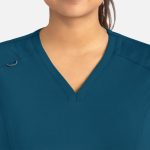 A close-up of a women's curved V-neck top in teal, featuring a logo on the shoulder.