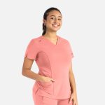 A curved V-neck top in coral pink with short sleeves and a pocket, featuring a logo on the chest.