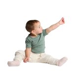 A seated infant wearing a green organic t-shirt and light-coloured trousers, reaching out with one hand.