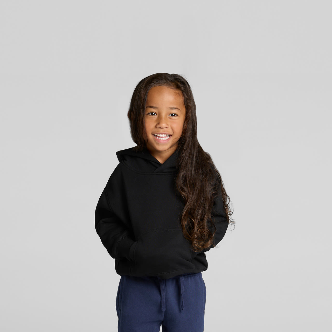 A child smiles while wearing a black hoodie. The hoodie features a front pocket and a hood. A child smiles while wearing a black hoodie. The hoodie features a front pocket and a hood.