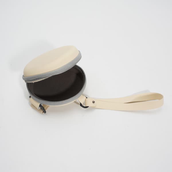 A cream-coloured folding eyeglasses case with a zippered opening and a carrying strap. The interior is dark. A cream-coloured folding eyeglasses case with a zippered opening and a carrying strap. The interior is dark.