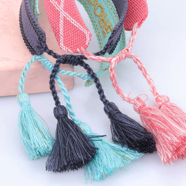 A collection of adjustable women's bracelets featuring colourful embroidery and decorative tassels in blue, black, and pink. A collection of adjustable women's bracelets featuring colourful embroidery and decorative tassels in blue, black, and pink.