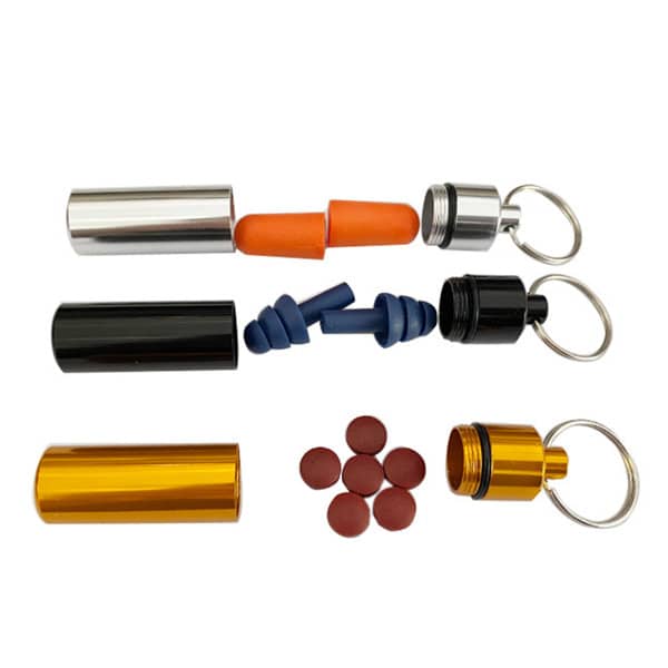 A small portable pill case with a keychain in silver, black, orange, blue, and gold, containing various earplugs and pills. A small portable pill case with a keychain in silver, black, orange, blue, and gold, containing various earplugs and pills.