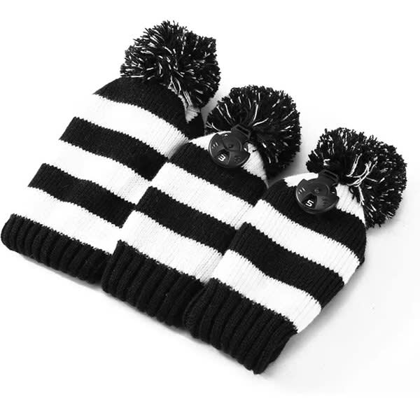 A knitted golf club head cover set in black and white stripes, featuring pom-poms on top. Comes with three sizes. A knitted golf club head cover set in black and white stripes, featuring pom-poms on top. Comes with three sizes.