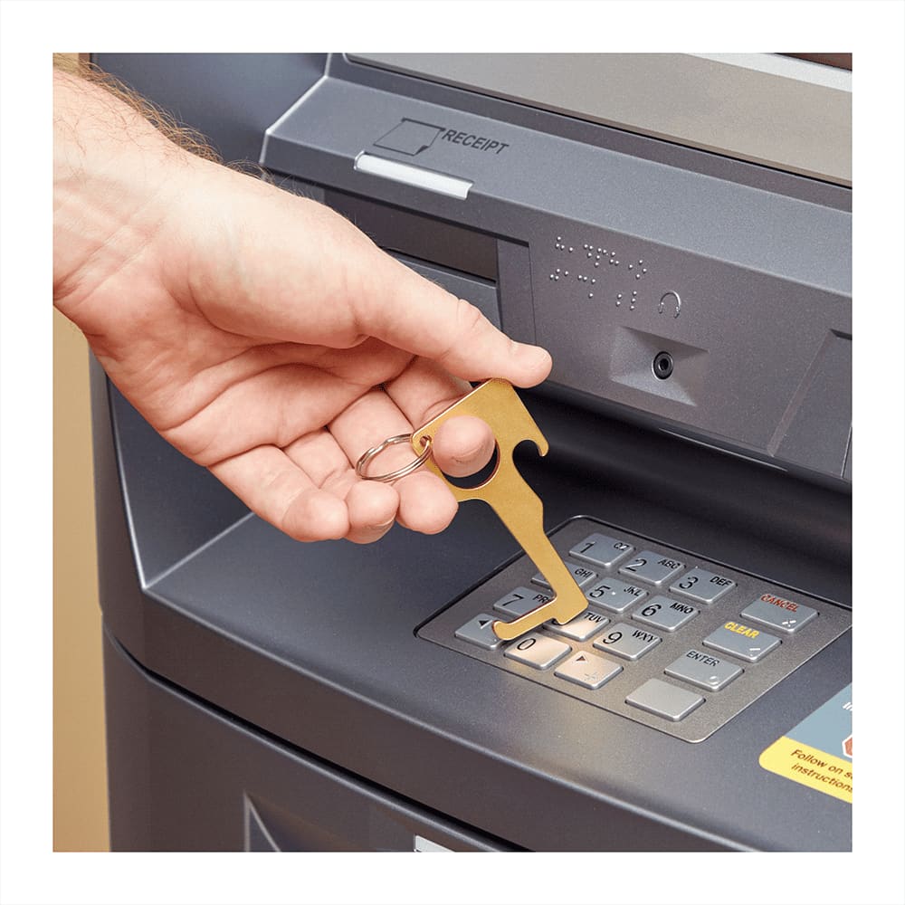A gold no contact keychain with a keyring is being used at an ATM keypad. No Contact Keychain - Image 1