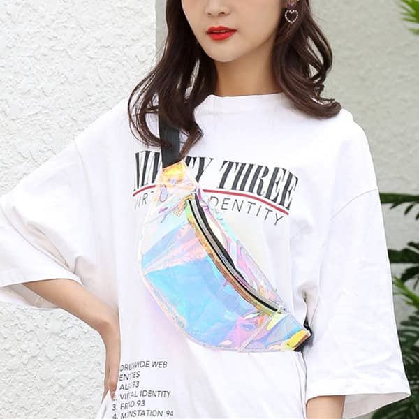 A woman wearing a holographic PVC waist bag with a black strap, styled casually in an oversized white T-shirt. A woman wearing a holographic PVC waist bag with a black strap, styled casually in an oversized white T-shirt.