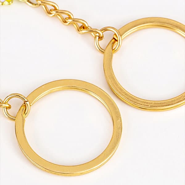 A custom metal keychain featuring two circular gold rings connected by a chain. A custom metal keychain featuring two circular gold rings connected by a chain.