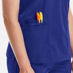 A deep blue women's top featuring a pocket with orange and yellow pens.