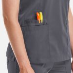 A women's double V-neck top in grey with two pens in the side pocket. It features a logo on the fabric.