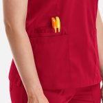 A close-up of a red women's top featuring a side pocket with orange and green pens.