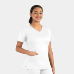 A woman in a white double v-neck top with short sleeves and a pocket, smiling against a light background.