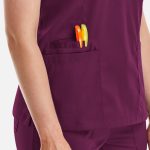 A purple women's double V-neck top featuring a side pocket with pens. The top has a logo on it.