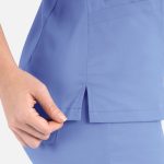 A light blue women's top with a double V-neck and side splits, featuring a hand adjusting the fabric.