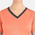 A women's top in coral with a contrast dark grey double V-neck design. Features a small logo on the neckline.