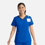 A blue women's top with a contrast V-neck and a pocket, featuring a logo and a name badge holder.